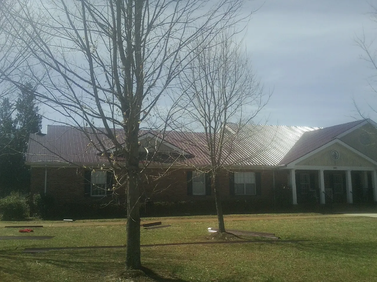 Red metal roof on a brick building seen from the front lawn in Mauston
