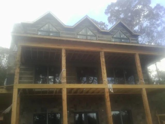 Dormers and porch framing on a large log home under construction — Roof Coating work by our crew in Mauston