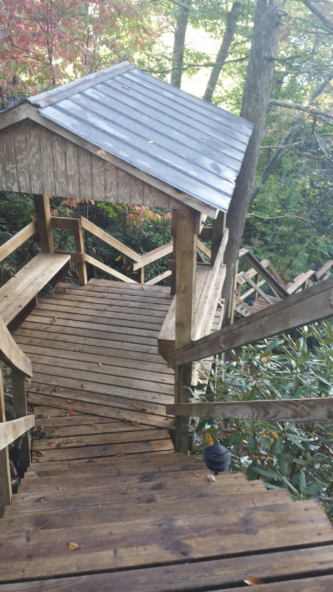 Metal roofed shelter over wooden steps on a wooded walkway — Skylight Repair & Installation work by our crew in Mauston