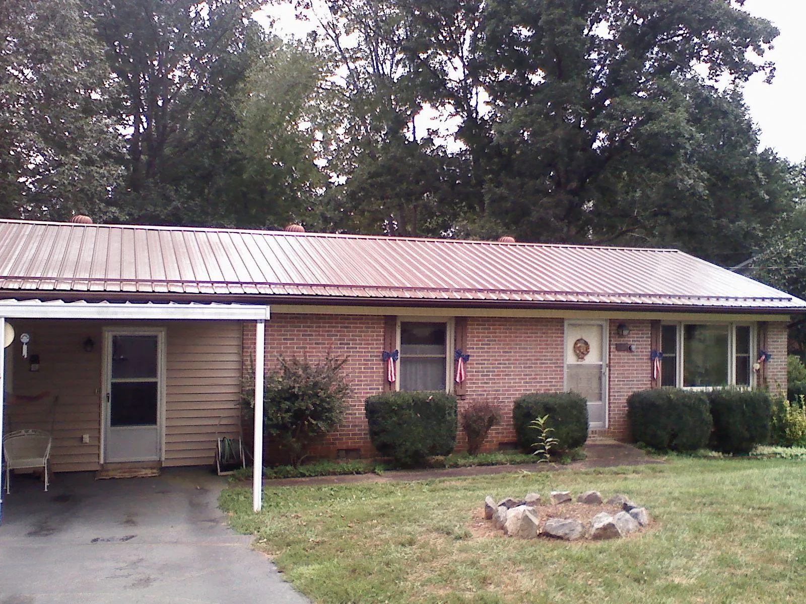 Bronze metal roof and carport on a brick ranch home — Roof Repair work by our crew in Mauston